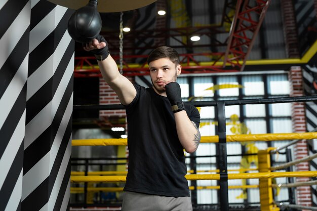 A conceptual portrait of a brutal tattooed boxer who trains in the ring and hits a punching bag