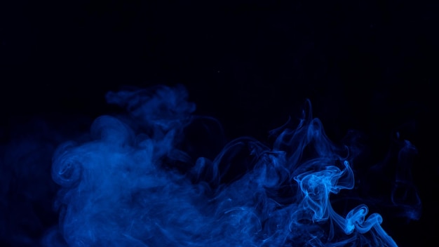 Conceptueel beeld van blauwe kleur rook geïsoleerd op donkere zwarte achtergrond Halloween design element concept
