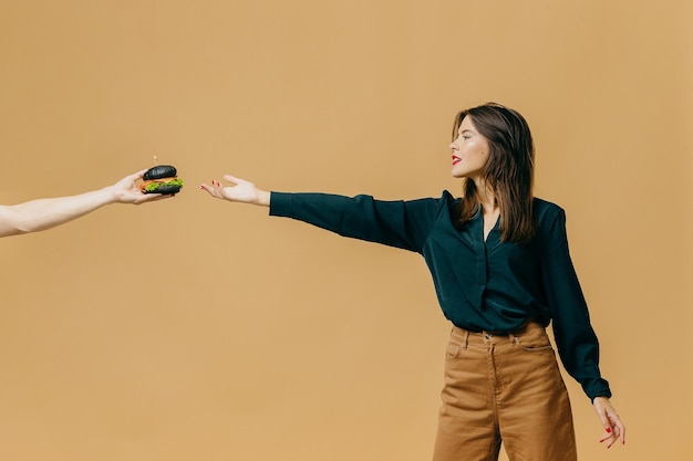 Conceptuele reclame voor fastfood een meisje met een hamburger op een gekleurde achtergrond hedendaagse kunst