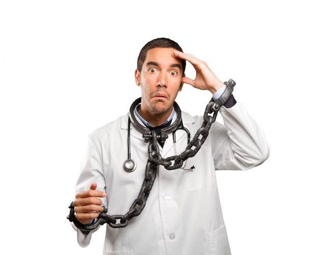 Concerned doctor with chains against white background