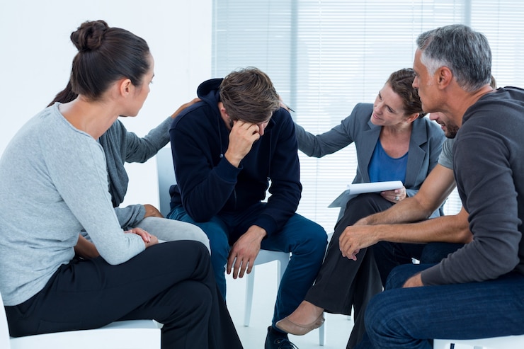 Photo concerned patients comforting another in rehab group