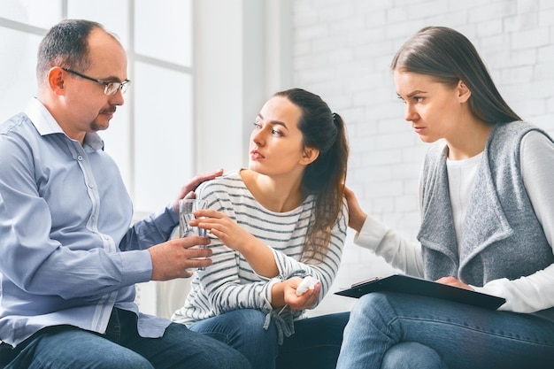 concerned support group mebers comforting emotional young woman at therapy session