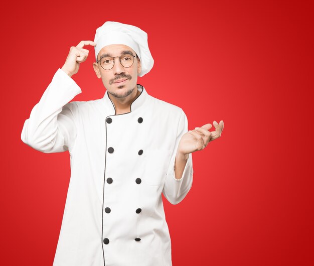 Concerned young chef doing a gesture of confusion