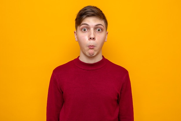 Concerned young handsome guy wearing red sweater isolated on orange wall