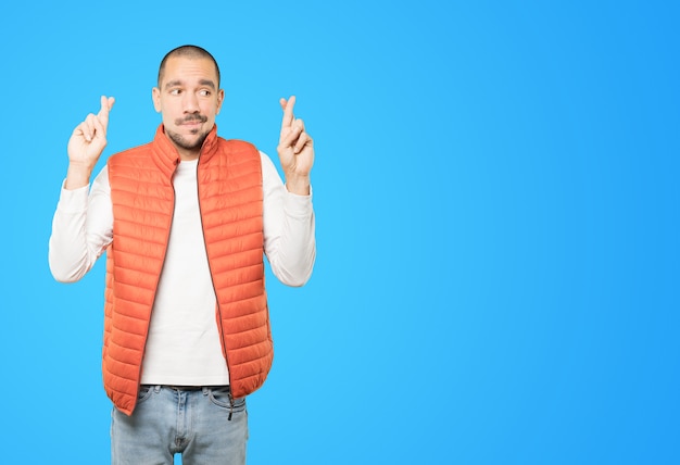 Concerned young man doing a crossed fingers gesture