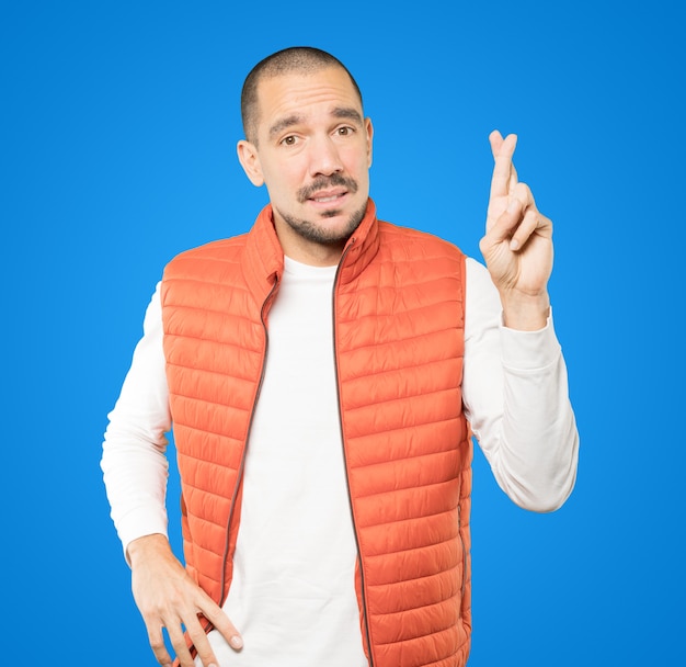 Photo concerned young man doing a crossed fingers gesture