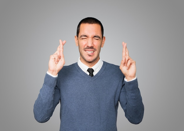 Concerned young man doing a crossed fingers gesture