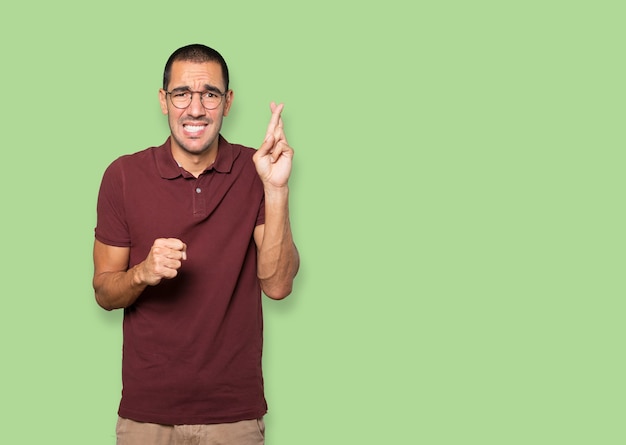 Concerned young man doing a crossed fingers gesture