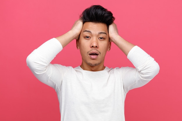 Concerned young man keeping hands on head 