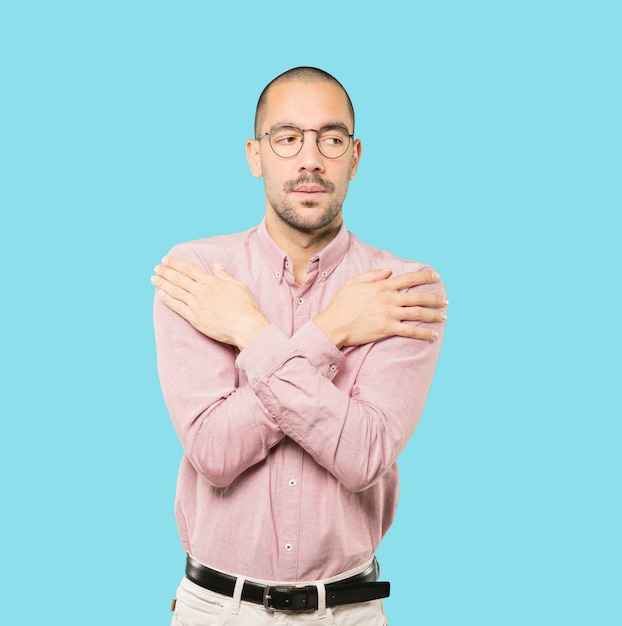 Concerned young man making a gesture of being cold