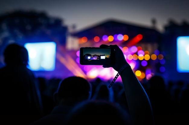 Concert visitor shoots video on a smartphone.