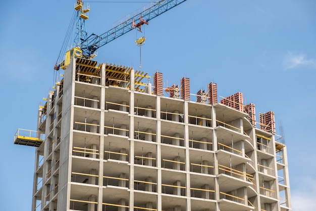 Concreet kader van lang flatgebouw in aanbouw en torenkraan in een stad.