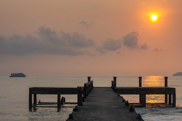 Photo concrete bridge piers and eflection of the sun in the sea.