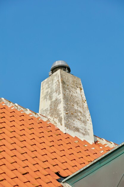 슬레이트 집 지붕에 설계된 콘크리트 굴뚝 또는 맑고 푸른 하늘 배경 copyspace에 대해 외부 건물 벽난로 연기와 열을 위해 옥상에 지어진 외부 탈출 슈트 건설