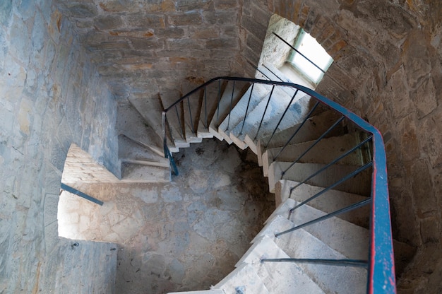 Concrete spiral stairs goo down inside old tower made from cobblestones