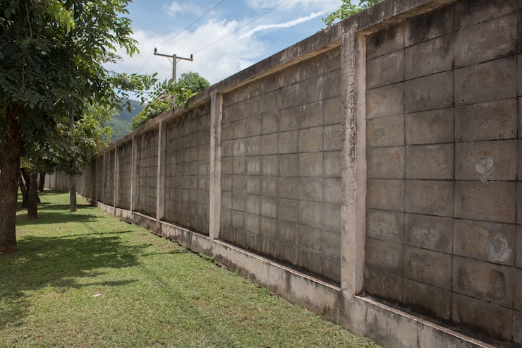 Concrete van de de muuromheining van de textuurmuur panelen in perspectiefmening met groen gras