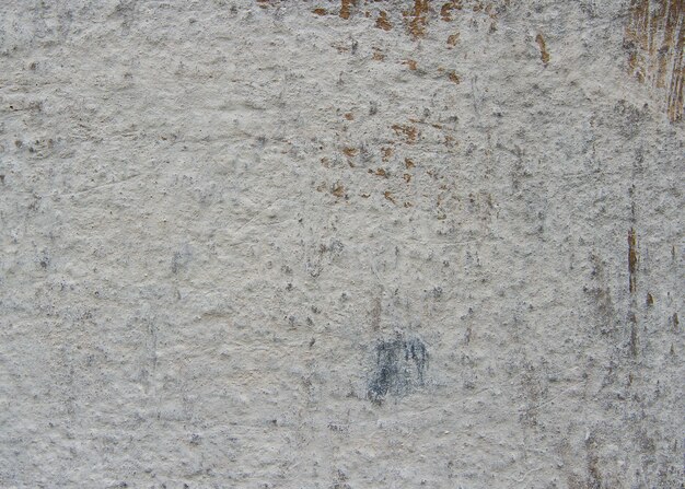 The concrete wall is covered with a gray facing filler. On the old wall there are scratches and rubs of various sizes.