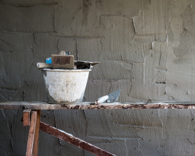 Foto primo piano dello strumento di fabbricazione e dell'oggetto del muro di cemento