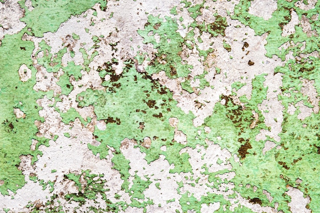 Concrete wall, painted in green, with damaged paint.