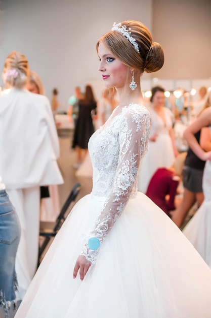 Concurrentie tussen bruidsstylisten Een model in een trouwjurk met haar en make-up toont het resultaat van het werk van de stylist