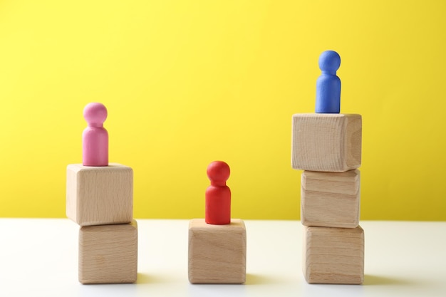 Concursconcept Menselijke figuren op houten kubussen tegen een kleurrijke achtergrond