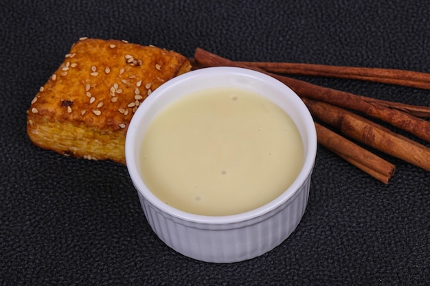 Condenced milk in the bowl with sinnamon and pastry