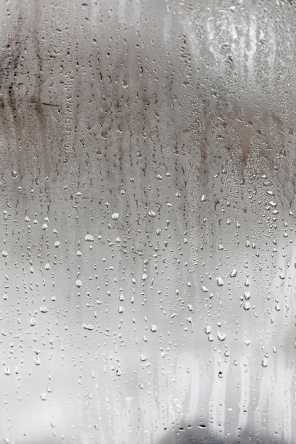 떨어지는 물방울이 있는 유리의 결로 수직 자연 배경 습도와 안개가 자욱한 공백 외부 악천후 비