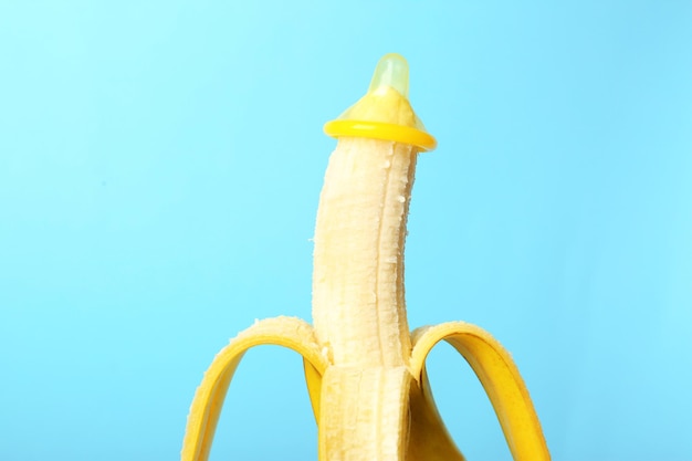 Condom on banana against color background Safe sex concept