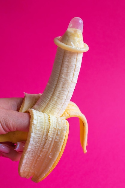 Photo condom on a banana on a coloured background the concept of safe sex