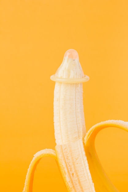 Condom and banana on an orange background closeup