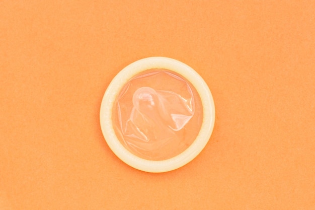 Condom on orange background Copy space