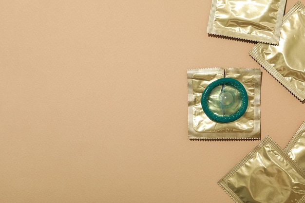 Condoms in a golden wrapper on a light background closeup place for text