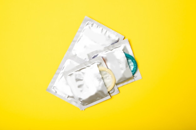 Condoms in packages on yellow background