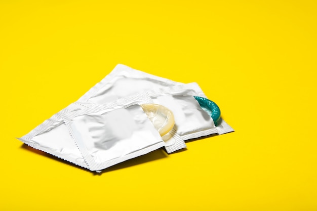 Photo condoms in packages on yellow background