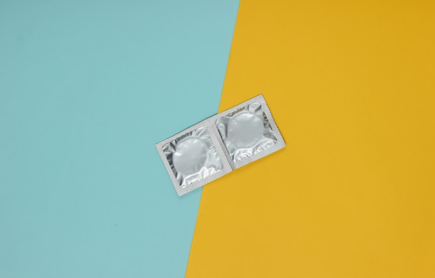 Condoms in packaging on a blue-yellow pastel paper