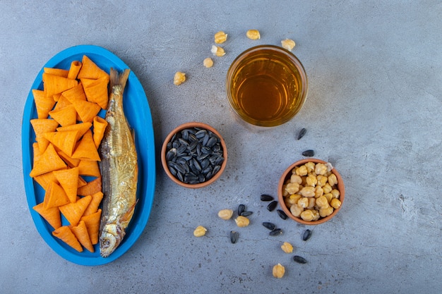 Cone chips and dried fish on a wooden plate on a towel , on the marble surface.