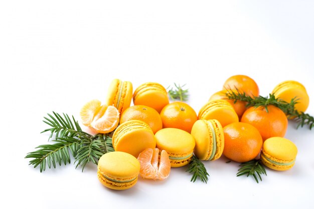 Confection macaroon lie on a white background with tangerines and spruce branches, background for the new year