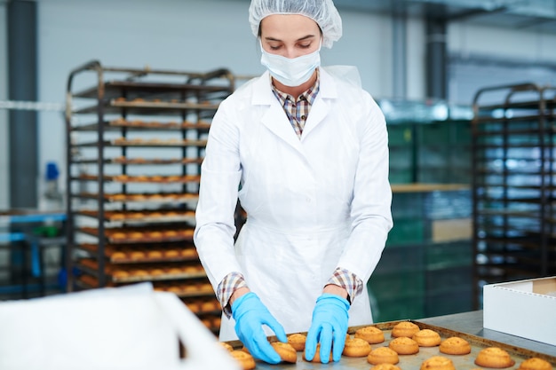 Pasticcere che raccoglie pasticceria appena sfornata dal vassoio