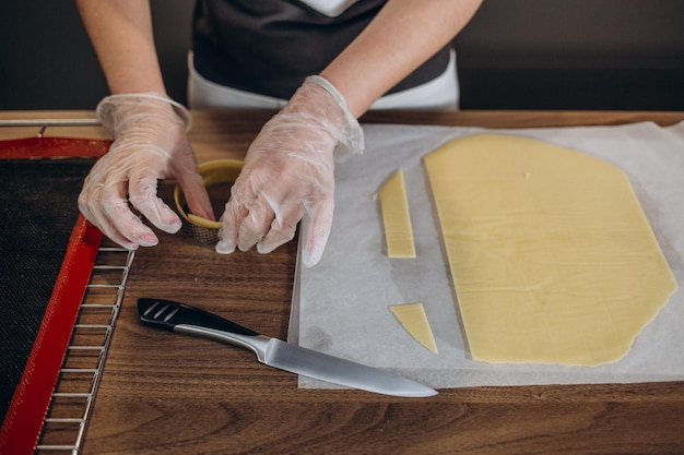 Confectioner cutting dough in the shape of a heart while making cookies in the kitchen of the