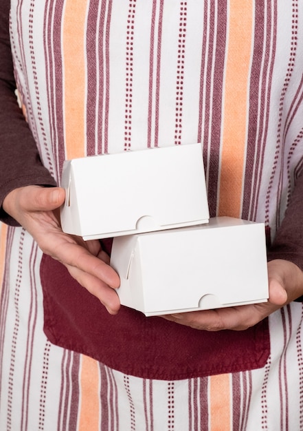 白い背景に2つの白い紙箱を持っている菓子屋または配達。