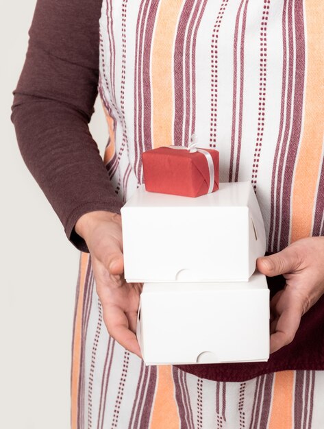 Confectioner or Deliver holding two white paper boxes on the white wall.