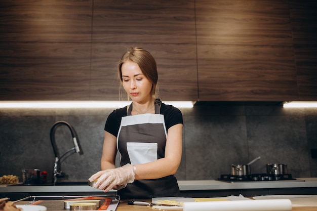 The confectioner forms gingerbread cookies using an original rectangular cutting Woman's hands in protective gloves Rolled out dough Stencils in the form of special shapes