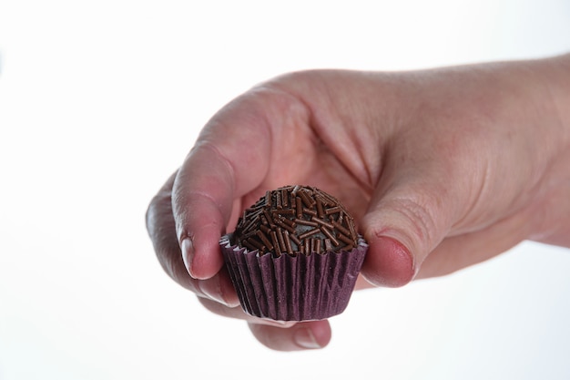 Confettiere tenendo un brigadeiro su uno sfondo bianco. dolce tradizionale brasiliano.