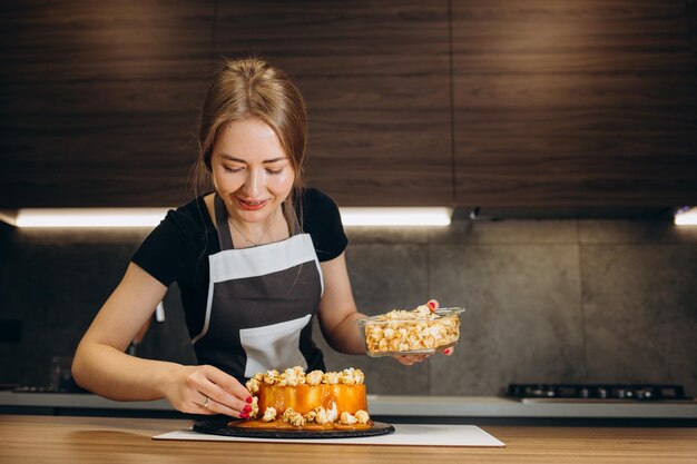 Confectioner in a kitchen Woman in a uniform Professional decorates the cake