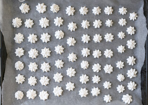 Confectioner prepares meringue in the kitchen. meringue on a baking sheet.