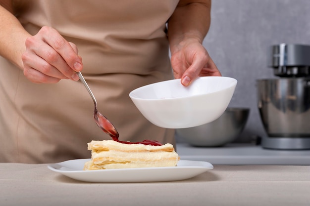 Foto pasticcere in procinto di preparare la torta con marmellata di frutti di bosco. mani del pasticcere.