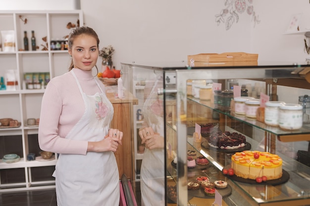 Pasticcere sorride alla telecamera che lavora nella sua pasticceria vegana cruda