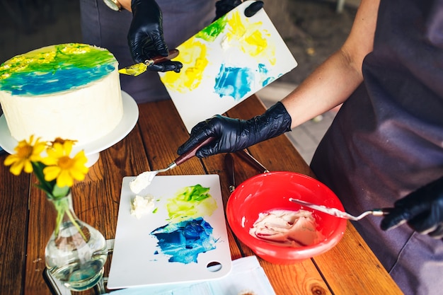 Confectioners decorate cake with colorful cream