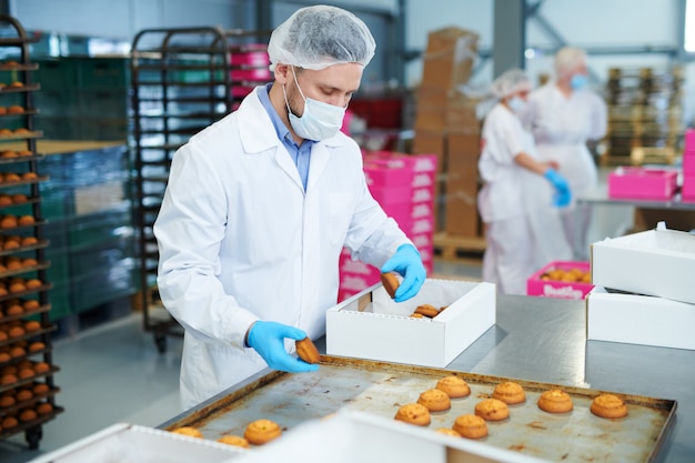 Confectionery factory worker packing pastry into box