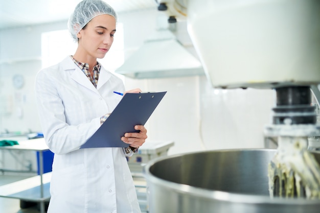 Confectionery factory worker taking notes